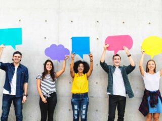 Youth voices - young people holding up paper shaped as speech bubbles