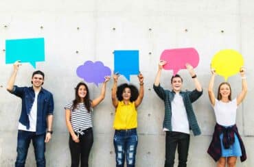 Youth voices - young people holding up paper shaped as speech bubbles