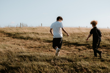 Two foster children running through a field on a camping trip