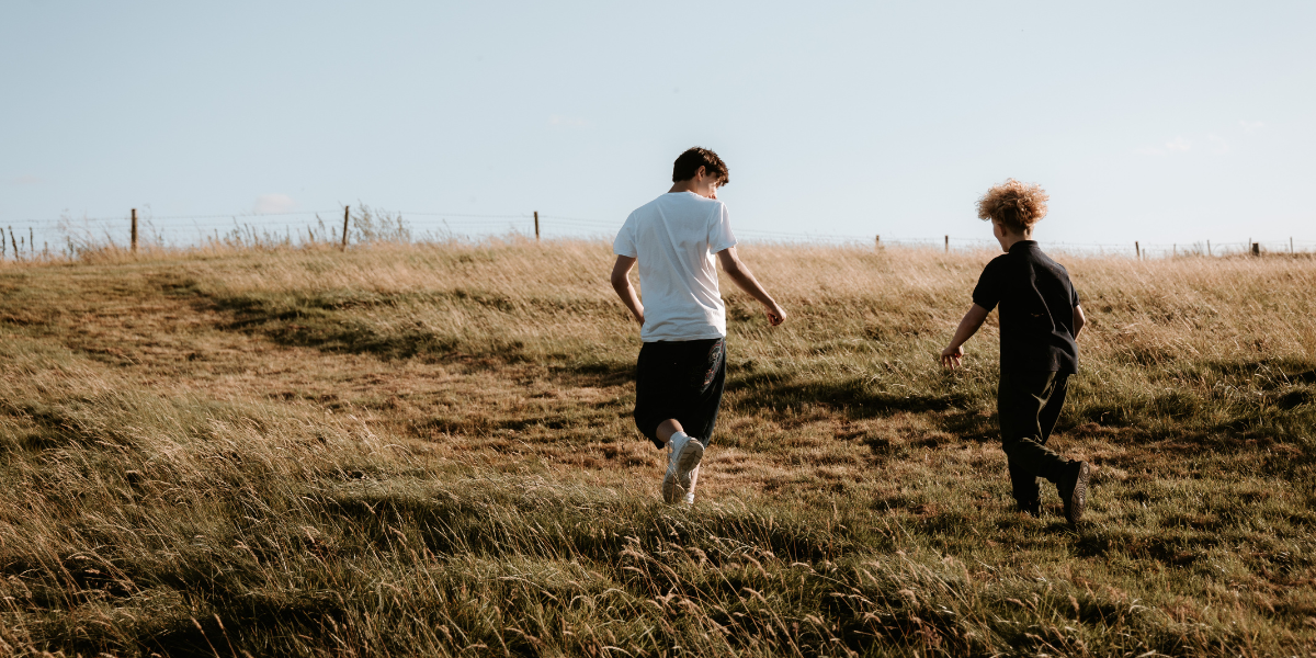 Two foster children running through a field on a camping trip